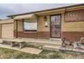 Inviting front entrance with a secure screen door and a stone bench, complemented by a well-kept yard at 7251 Larsh Dr, Denver, CO 80221