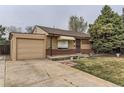 Charming brick home featuring a well-maintained front yard and attached one-car garage and a stone bench on the front porch at 7251 Larsh Dr, Denver, CO 80221