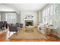 Bright living room featuring hardwood floors, a fireplace, and large windows with shutters at 7527 E Severn Pl, Denver, CO 80230