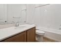 Well-lit bathroom featuring wood-grain vanity, white countertop, and full bathtub with white tiles at 45946 Gentry Ave, Bennett, CO 80102