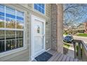 Inviting front door with a storm door, flanked by windows and a brick chimney, creating a warm entry at 17336 E Rice Cir # F, Aurora, CO 80015
