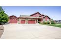 Charming home exterior features a long driveway and a three-car garage with red doors at 16283 Olive Way, Brighton, CO 80602