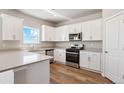 Modern kitchen featuring stainless steel appliances, white cabinets, hard surface counters and wood-look floors at 48220 Shetland Dr, Bennett, CO 80102