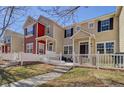 Street view of townhouses with a quaint white picket fence, inviting curb appeal, and a well-maintained lawn at 1496 Red Cliff Way, Castle Rock, CO 80109