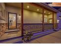 Inviting front porch with stone supports, wooden railings, and a charming entrance, illuminated by warm lighting at 1012 S Addison Way, Aurora, CO 80018