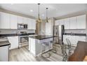 Modern kitchen features white cabinets, stainless steel appliances, a center island with stool seating, and pendant lighting at 1171 Nathan Pl, Erie, CO 80026