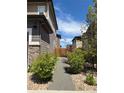 Landscaped side yard with gravel path, lush green shrubs, and a wood fence at 11235 S Neu Towne Cir, Parker, CO 80134