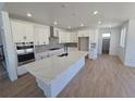 Bright kitchen with a large center island, white cabinets, and stainless steel appliances at 1733 Fox Trotter Pt, Castle Rock, CO 80104