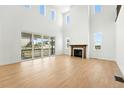 Bright living room featuring soaring ceilings, a fireplace, light wood floors, and sliding glass doors at 1733 Fox Trotter Pt, Castle Rock, CO 80104