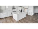 Modern kitchen featuring white cabinets, stainless steel appliances, an island, and hardwood floors at 25323 E Warren Pl, Aurora, CO 80018