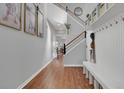 Bright hallway with hardwood floors, white bench, and a staircase with wood and iron railing at 18085 E 107Th Pl, Commerce City, CO 80022