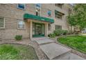 Inviting brick building entrance with green awning, glass door, and well-manicured lawn at 2100 N Franklin St # 15, Denver, CO 80205