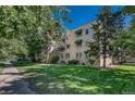 Multi-story brick building with green awnings surrounded by mature trees and lush green lawn at 2100 N Franklin St # 15, Denver, CO 80205