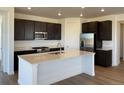 Modern kitchen with stainless steel appliances, dark cabinetry, and a large center island at 737 Raindance St, Erie, CO 80516