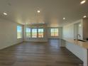 Open-concept living room with wood floors, recessed lighting, and large windows at 737 Raindance St, Erie, CO 80516