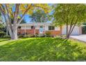 Inviting single-story home with a well-kept lawn, brick accents, covered porch, and an American flag on display at 6642 S Pearl St, Centennial, CO 80121