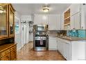 Functional kitchen with stainless steel appliances, white cabinetry, and tile backsplash at 8991 Hickory Pl, Thornton, CO 80229