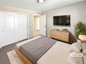 Virtually staged bedroom with a wooden bed frame, dresser, and large TV at 26226 E Canal Pl, Aurora, CO 80018