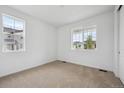 Sunlit bedroom with neutral carpet, white walls, and two large windows showcasing the neighborhood at 24740 E 39Th Ave, Aurora, CO 80019