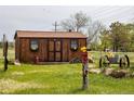 Rustic outbuilding featuring decorative window boxes, flower accents, and adjacent yard decor at 6310 W County Road 4, Berthoud, CO 80513