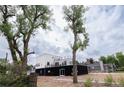 A modern home with black and white siding and a roof deck, surrounded by mature trees at 5462 S Cedar St, Littleton, CO 80120