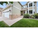 Inviting home entrance with brick accents, manicured lawn, and three car garage at 9916 Sand Cherry Way, Highlands Ranch, CO 80129