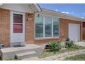 Close-up of a charming brick home with well-maintained landscaping and an attached single-car garage at 10900 Mildred Dr, Northglenn, CO 80233