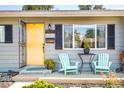 Inviting front porch with yellow door and blue chairs at 1800 S Tennyson St, Denver, CO 80219