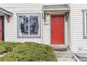 Close-up view of a townhouse entrance featuring a vibrant red door and a well-maintained green shrub at 17694 E Loyola Dr # C, Aurora, CO 80013