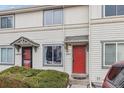 Exterior view of townhouse with neutral siding, red front door, small covered porch, and neatly trimmed front garden at 17694 E Loyola Dr # C, Aurora, CO 80013