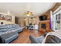 Inviting living room with hardwood floors, fireplace, ceiling fan, and ample natural light at 1115 Cherry Ct, Fort Lupton, CO 80621