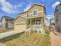 Beautiful two-story house with tan siding, a two-car garage, and well-maintained front yard at 9844 Truckee St, Commerce City, CO 80022