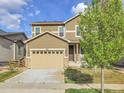 Charming two-story home with tan siding, a two-car garage, and well-manicured landscaping at 9844 Truckee St, Commerce City, CO 80022