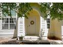 Inviting front door with wreath, framed by white pillars and a yellow archway, creating a warm entry at 3962 Hoyt Ct, Wheat Ridge, CO 80033