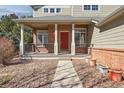Charming front porch with brick columns and a bright red front door at 10795 Quail Creek E Dr, Parker, CO 80138