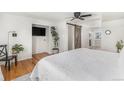 Bright bedroom with white quilt, wood floors, a barn door to the bathroom, and a ceiling fan at 6731 Devinney St, Arvada, CO 80004