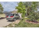 Two-story home showcasing an attached two-car garage, a long driveway, mature shade trees, and minimal landscaping at 2370 Redwood Ave, Lafayette, CO 80026