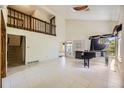 Bright living room featuring soaring ceilings, tile floors, a black baby grand piano, fireplace and a second story balcony at 2370 Redwood Ave, Lafayette, CO 80026
