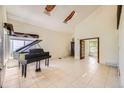 Bright living room featuring soaring ceilings, tile floors, and a black baby grand piano under a window at 2370 Redwood Ave, Lafayette, CO 80026