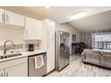 Open-concept kitchen with stainless steel appliances, white cabinets, and breakfast bar overlooking the living area at 3144 S Wheeling Way # 401, Aurora, CO 80014