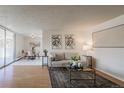 Open living room featuring hardwood floors, a modern sofa, and access to the dining area at 1090 N Lafayette St # 305, Denver, CO 80218