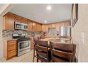 Functional kitchen with stainless steel appliances, wood cabinets, and dining table at 7511 Locust St, Commerce City, CO 80022