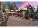 A beautiful exterior view of a luxury mountain home featuring an attached garage, paved driveway, and mature landscaping at 30 W Ranch Trl, Morrison, CO 80465