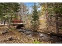 Scenic creek view flowing under foot bridge amidst wooded area at 2971 Fall River Rd, Idaho Springs, CO 80452
