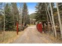 Wood home exterior beyond creek with gated entrance at 2971 Fall River Rd, Idaho Springs, CO 80452