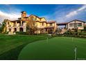 Back of home featuring outdoor putting green, lush lawn, stone accents and covered patio at 1820 Mallard Dr, Broomfield, CO 80020