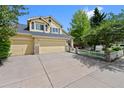 Well-maintained yellow two-story home with a spacious driveway and beautifully landscaped front yard at 7638 S Hudson Way, Centennial, CO 80122