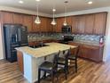 Open-concept kitchen with granite counters, tiled backsplash, stainless appliances, and pendant lighting at 22822 E Union Cir, Aurora, CO 80015
