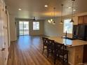 Cozy living space features an island with seating, wood-look floors, and sliding glass door at 22822 E Union Cir, Aurora, CO 80015