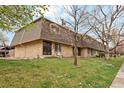 Attractive exterior showcasing the brick facade, mature trees, and well-manicured lawn of the townhome at 11228 W 18Th Ave, Lakewood, CO 80215